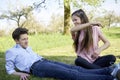 Girlfriend beating her boyfriend for fun on a meadow with yellow flowers, in the background trees