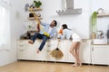 Girlfriend and boyfriend in rubber gloves singing and playing mop like guitar in kitchen. Having fun doing chores Royalty Free Stock Photo