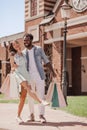 Girlfriend and boyfriend with shopping bags and taking selfie with smartphone using selfiestick outdoors at daytime