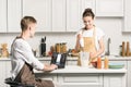 girlfriend cooking and boyfriend using laptop with loaded linkedin page Royalty Free Stock Photo