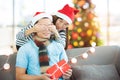 Girlfriend surprise boyfriend by giving Christmas present at sofa with xmas decoration tree at home Royalty Free Stock Photo