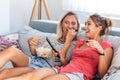 Girlfriend watching a very funny movie and eat popcorn. Smiling young women relaxing and watching TV at home, female friends Royalty Free Stock Photo