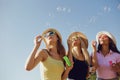 Girlfriends blowing soap bubbles on the beach.