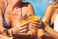 Girlfriends clinking glasses with cocktails at the poolside bar Royalty Free Stock Photo