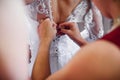 Girlfriends lace up white dress the bride on back on corset on wedding day Royalty Free Stock Photo