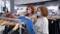 Girlfriends in medical masks and gloves choose clothes in store