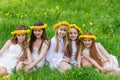 Girlfriends are sitting in the grass with wreaths of dandelions Royalty Free Stock Photo