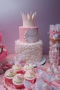 Girlish birthday cake. Pink dessert with mastic crown shape, white cream roses flowers and inscription name Emilia. Candy bar with Royalty Free Stock Photo