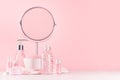 Girlish cute bathroom interior in pastel pink color - cosmetic products for skin and body care and round mirror on soft white wood Royalty Free Stock Photo