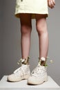 girlish legs in white shoes with chamomile flowers. girl in stylish boots Royalty Free Stock Photo