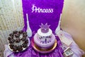 Girlish purple cake with crown and inscription - name Katusha is 1 year old. First birthday party. Candy bar with muffins