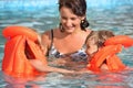 Girls bathing in lifejackets with woman in pool