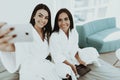 Girls In A Bathrobes Are Doing A Selfie On A Bed. Royalty Free Stock Photo
