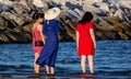 Girls on the beach in the east wearing a red and blue dress with their feet in the water, watching the sea relax, a photo taken at Royalty Free Stock Photo