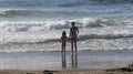 Girls on the beach in front of waves holding hands waiting to jump the waves Royalty Free Stock Photo