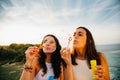 Girls blowing bubbles over the sea Royalty Free Stock Photo