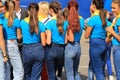 Girls in blue jeans and T-shirts stand in a crowd on the street at the festival. Spring, summer carnival, holiday, promotion. City