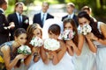 Girls and bride pose with wedding bouquets while groom and groom