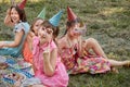 Girls celebrate in carnival masks, party hats. Fun children picnic with friends.