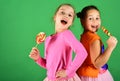 Girls with cheerful faces pose with candies on green background. Royalty Free Stock Photo