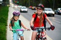 Girls children cycling on yellow bike lane. Cars are road. Royalty Free Stock Photo