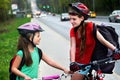 Girls children cycling on yellow bike lane. There are cars on road. Royalty Free Stock Photo