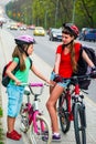 Girls children cycling on yellow bike lane. There are cars on road. Royalty Free Stock Photo