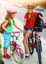 Girls children cycling on yellow bike lane. There are cars on road. Royalty Free Stock Photo