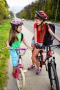 Girls children cycling on yellow bike lane. There are cars on road. Royalty Free Stock Photo