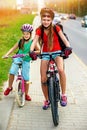 Girls children cycling on yellow bike lane. There are cars on road. Royalty Free Stock Photo