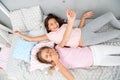 Girls children lay on bed with cute pillows top view. Pajamas party concept. Girls have fun. Girlish secrets honest and