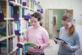 Girls choosing book in library