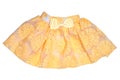 Girls clothes. Festive beautiful yellow little girl short summer skirt with floral pattern and a golden ribbon bow isolated on a