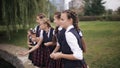 Students in school uniform feeding ducks in a pond in the school yard. Girls College coeds wearing the same school