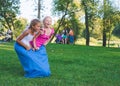 girls compete in a relay race . Jumping in bags . They laugh and fall . Royalty Free Stock Photo