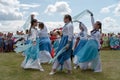 Girls in costumes dancing on the grass in front of the audience during the ethnic festival Karatag on the shore of a Large lake