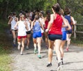 Girls cross country race on dirt path in woods taken from behind