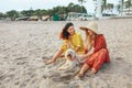 Girls With Dog On Beach. Models In Bohemian Clothing And Straw Hat With Pet On Sandy Coast