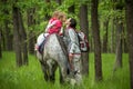 Girls enjoying horseback riding in the woods with mother, young pretty girls with blond curly hair on a horse, freedom Royalty Free Stock Photo