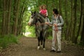 Girls enjoying horseback riding in the woods with mother, young pretty girls with blond curly hair on a horse, freedom Royalty Free Stock Photo