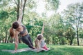 Girls are excercising in park. They are stretching together. Woman and kid are holding their left hand up and leaning to