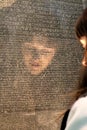 Girls face reflected as she tries to read the Rosetta Stone with writing in different ancient languages - selective focus - in Bri