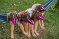 Girls in festive hats are sitting on hammock, hiding faces joking on birthday Royalty Free Stock Photo