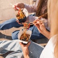 Girls friends chat and share fastfood wok noodles in a street food openair restaurant Royalty Free Stock Photo