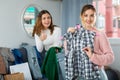 Girls friends demonstrating each other and trying clothes in home interior