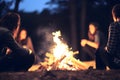 Girls friendship group sit round a bright campfire at night