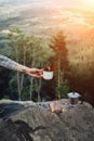 Girls hand holds a hot cup of coffee near the campfire on background of nature during the sunset Royalty Free Stock Photo