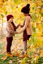 Girls in hats in autumn Park under yellow maples and hold hands