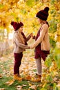 Girls in hats in autumn Park under yellow maples and hold hands