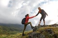 Girls helping each other hike up a mountain at sunrise. Giving a Royalty Free Stock Photo